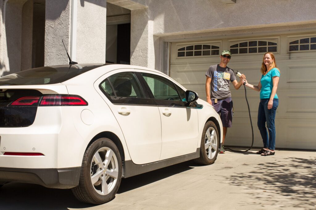 Man and Woman holding EV Charger plug in Driveway